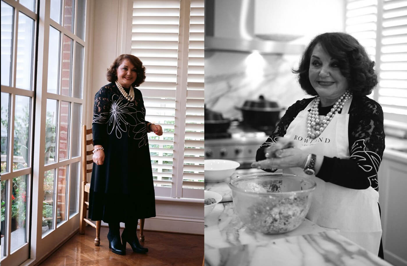 Woman in floral black dress smiles warmly by a window and while mixing in the kitchen.
