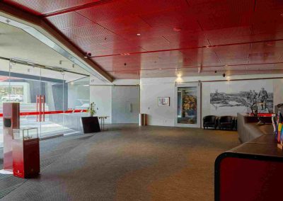 Modern reception with red ceiling, glass entry, open layout, and wall mural.